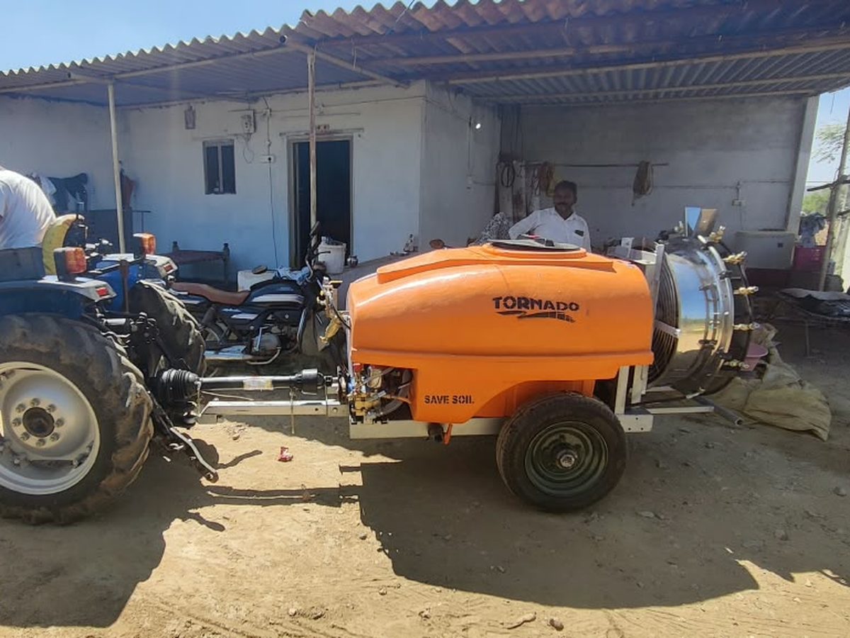 Orange Tornado air blast sprayer hitched to a Sonalika tractor in the field
